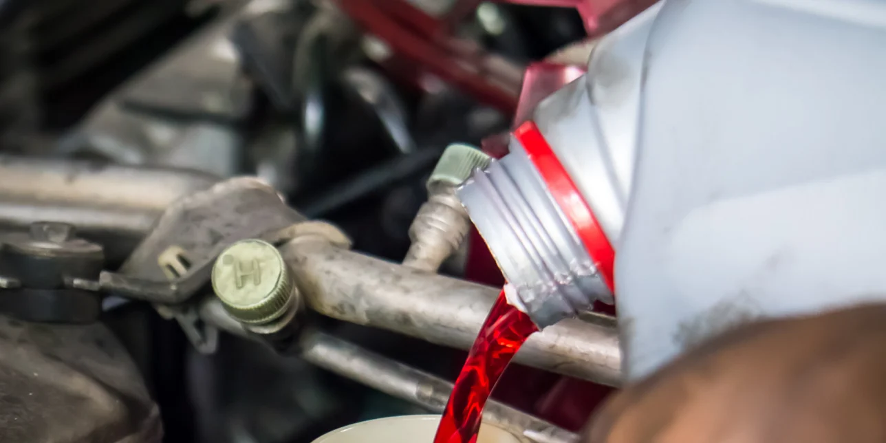 Hand pouring transmission fluid into a reservoir.